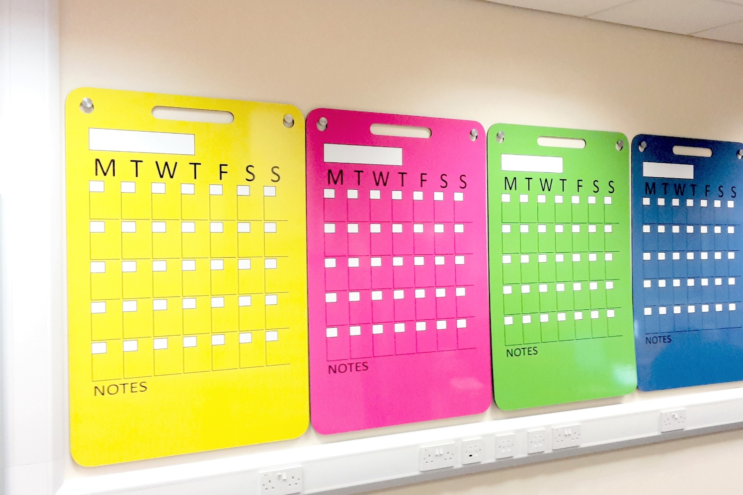 Portable hook up whiteboards in bright colours shown hanging on wall