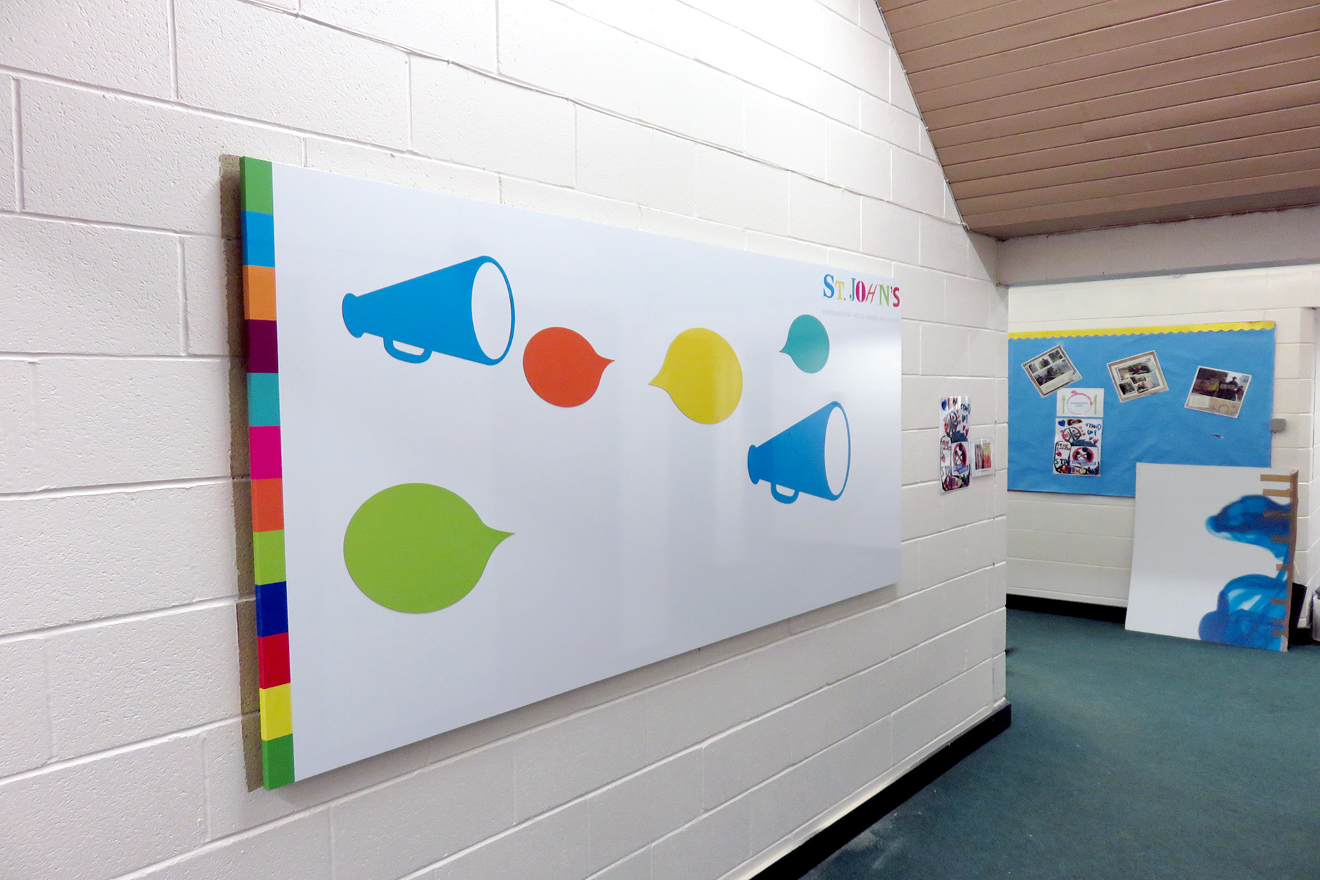 Custom printed whiteboard with brightly coloured speech bubbles waiting for display materials in a primary school corridor