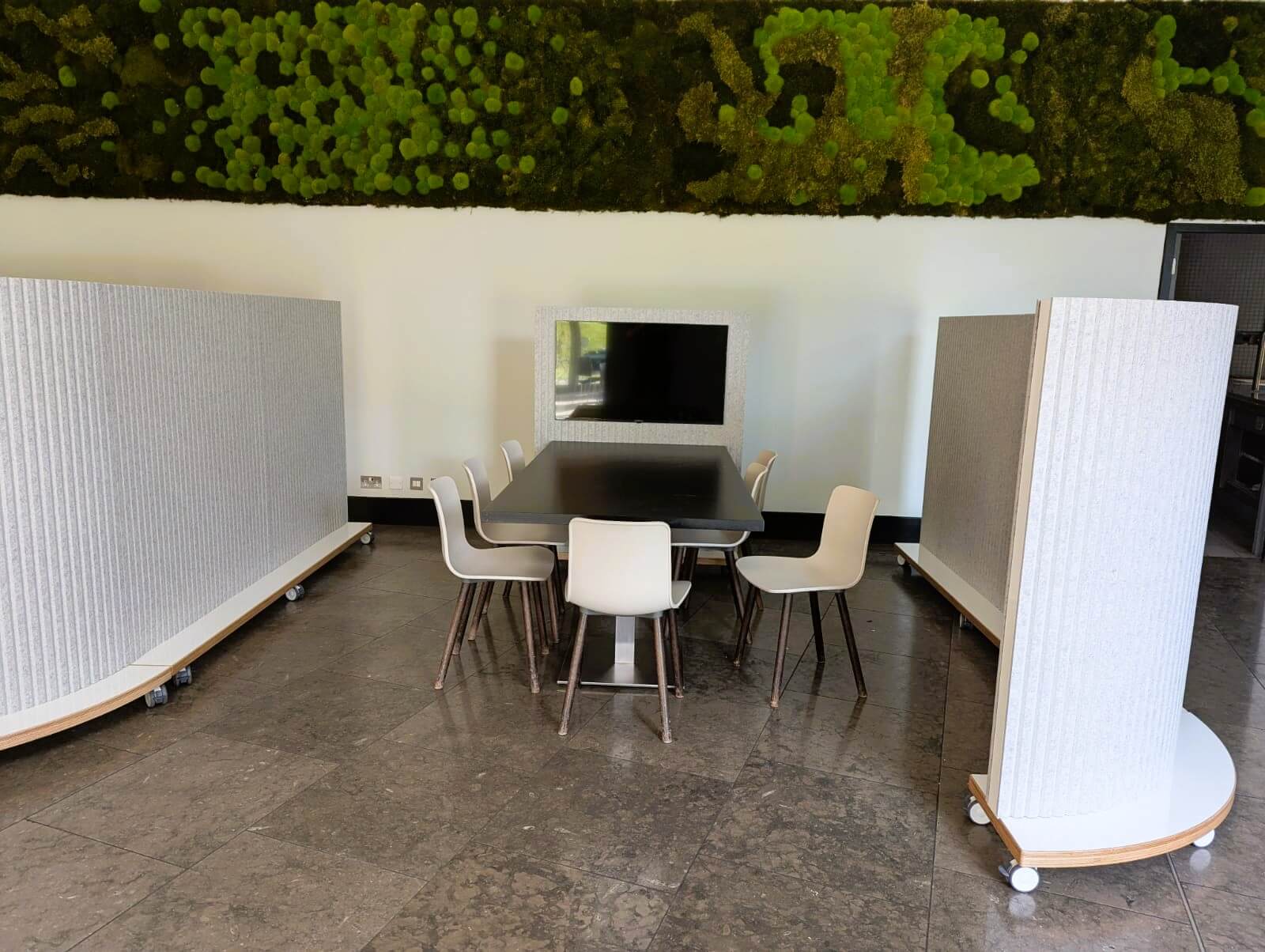 Mobile curved office dividers on wheels around a meeting area with large table and chairs