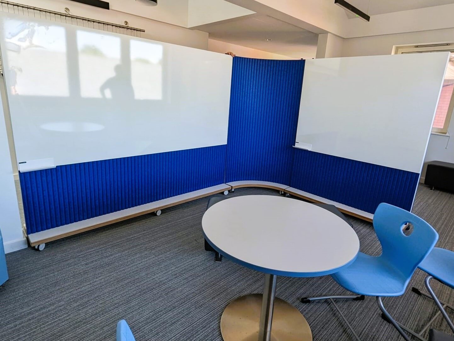 Mobile curved dividers and straight dividers with bright blue acoustic panel