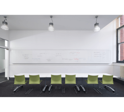 Whiteboard stretches from one end of classroom to other, providing continuous writing surface at the perfect height